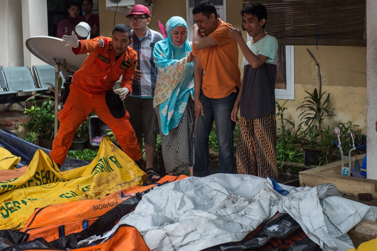 Personas reaccionan tras encontrar a familiares en bolsas para cadáveres de víctimas del tsunami que alcanzó el Estrecho de la Sonda, en Pandeglang, provincia de Bantén, Indonesia.