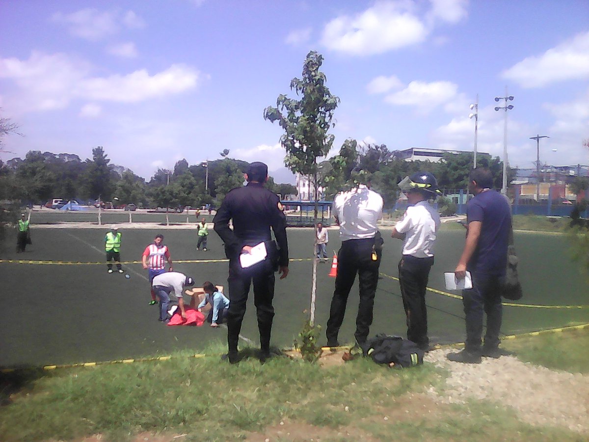 Bomberos Voluntarios observan el cadáver luego de confirmar la muerte, en medio de una de las canchas de los Campos del Roosevelt, zona 11. (Foto Prensa Libre: CVB)