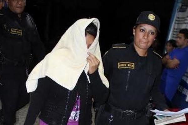 Una agente policial custodia hacia el juzgado de turno a Juana Ramos, señalada de matar a golpes a su hija recién nacida. (Foto Prensa Libre: Oscar Figueroa)