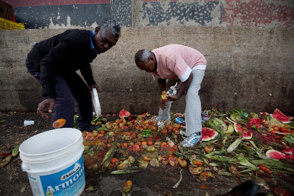 Dos venezolanos recogen tomates en el basurero del mercado de Coche en Caracas.(AP).