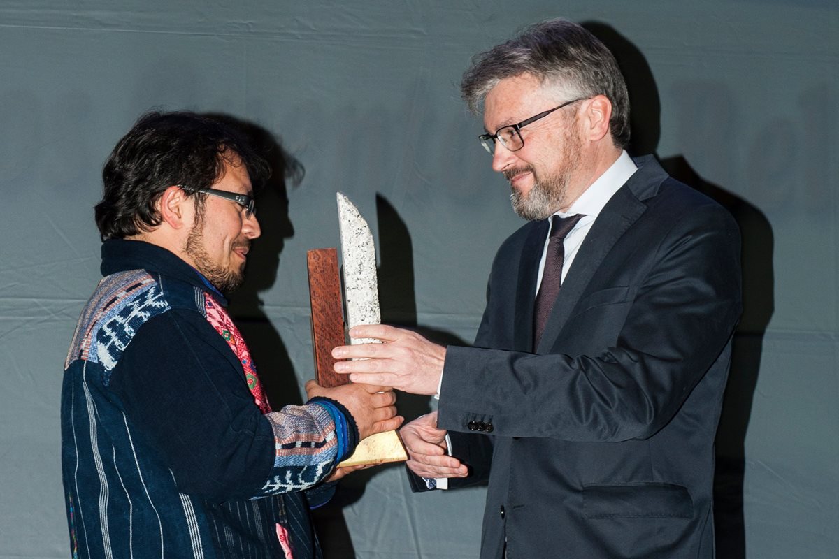 El cónsul honorario de Guatemala en España, Javier de Garnika, entrega el reconocimiento del primer lugar del certamen Cuentamontes al escritor guatemalteco Christian Rodríguez. (Foto Prensa Libre, cortesía de Christian Rodríguez).