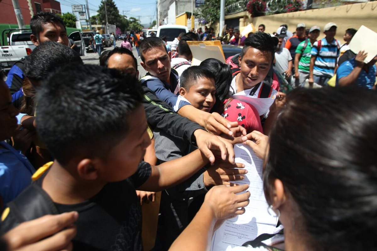 Un grupo de jóvenes busca una de las fichas de solicitud de empleo para comenzar el proceso, afuera de la Escuela de Estudios Penitenciarios, en la zona 9. (Foto Prensa Libre: Érick Ávila)