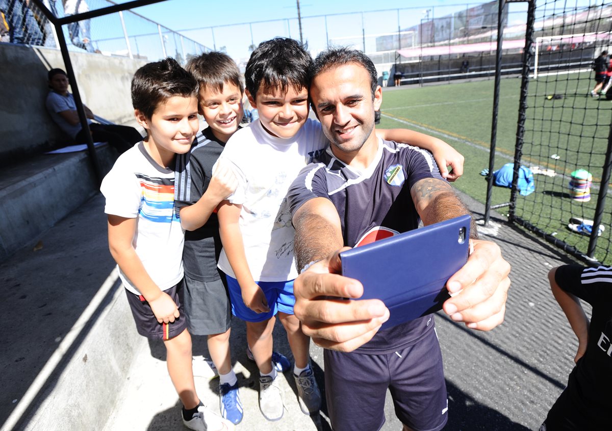 El volante de Comunicaciones José Contreras se toma una fotografía con su celuar acompañado de varios niños. (Foto Prensa Libre: Francisco Sánchez)