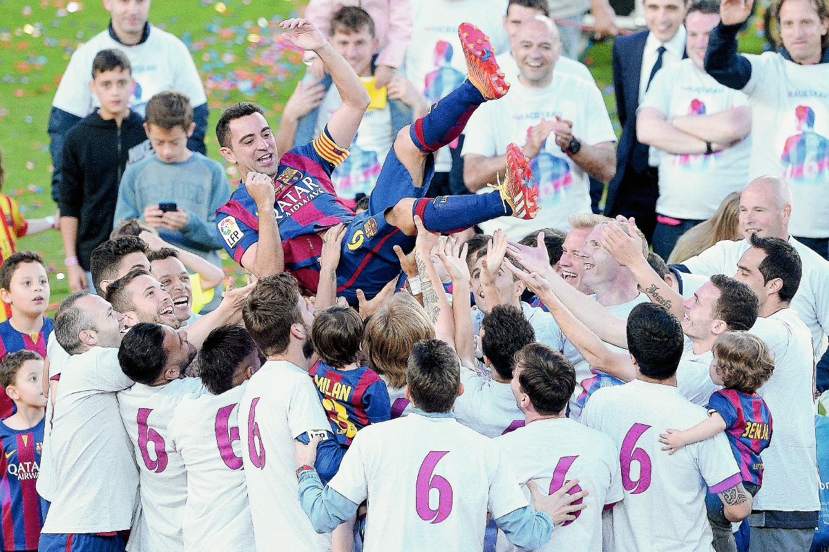 Xavi Hernández es levantado en hombros por sus compañeros quienes visten camisolas en homenaje. (Foto Prensa Libre: EFE)