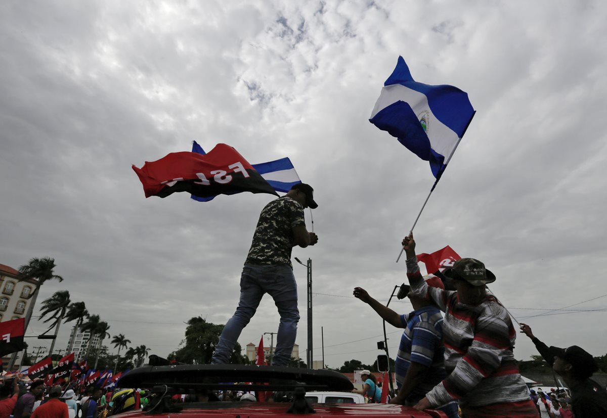 Manifestantes ondean banderas en la marcha a favor de Daniel Ortega.  (AFP)