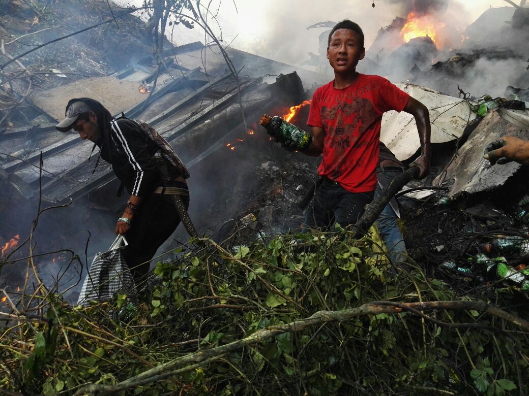 Vecinos recogen frascos con químicos en el lugar donde quedó el camión incendiado. (Foto Prensa Libre: Oswaldo Cardona)