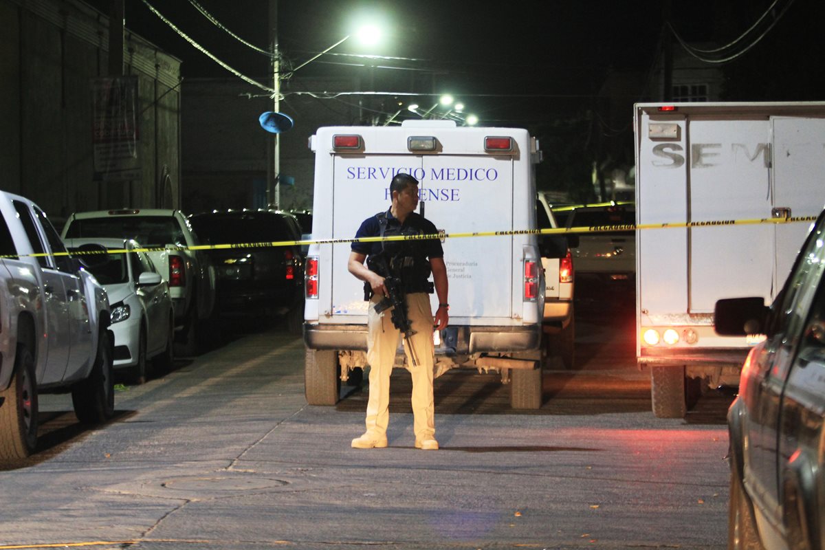 Un policía monta guardia en el lugar donde peritos forenses recogen información en torno al sitio donde 15 personas aparecieron muertas.(Foto Prensa Libre:AFP).