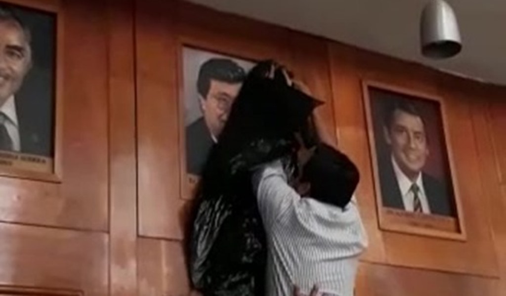 Momento en que integrantes del Consejo Superior Universitario tapan con una bolsa negra la fotografía del exrector Jafeth Cabrera, quien fue declarado no grato junto al presidente Jimmy Cabrera. (Foto Prensa Libre: Cortesía)