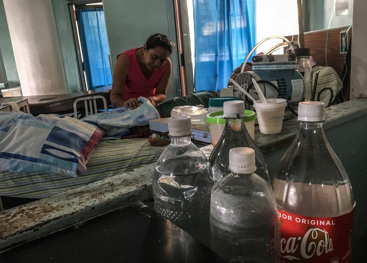 Un familiar revisa a un paciente en una sala del Hospital Universitario de Caracas. (AFP)