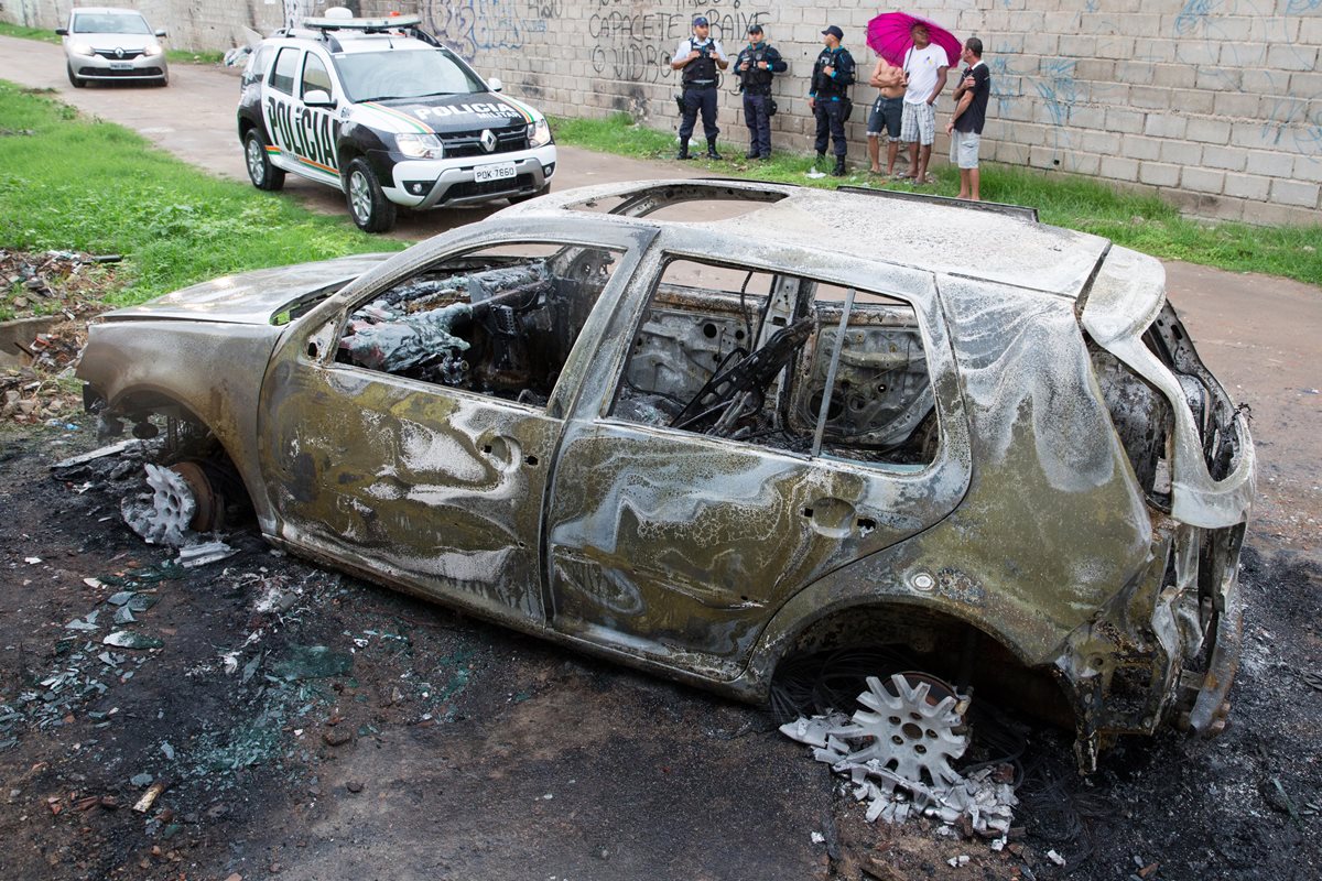 Un automóvil abandonado y quemado por los supuestos culpables de realizar un ataque a balazos. (Foto Prensa Libre: EFE)