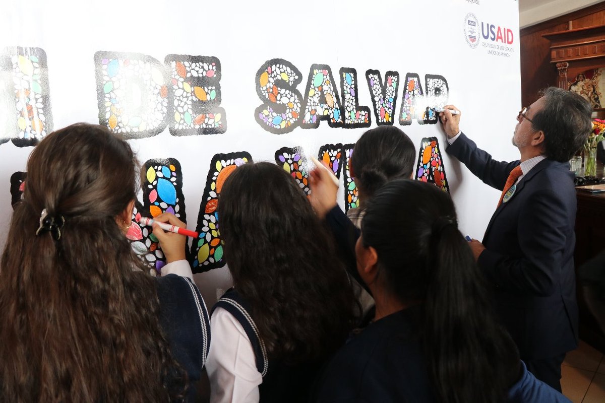 El embajador de EE. UU., Luis Arrega, junto con unas estudiantes pinta un mural sobre la trata de personas. (Foto: PDH)