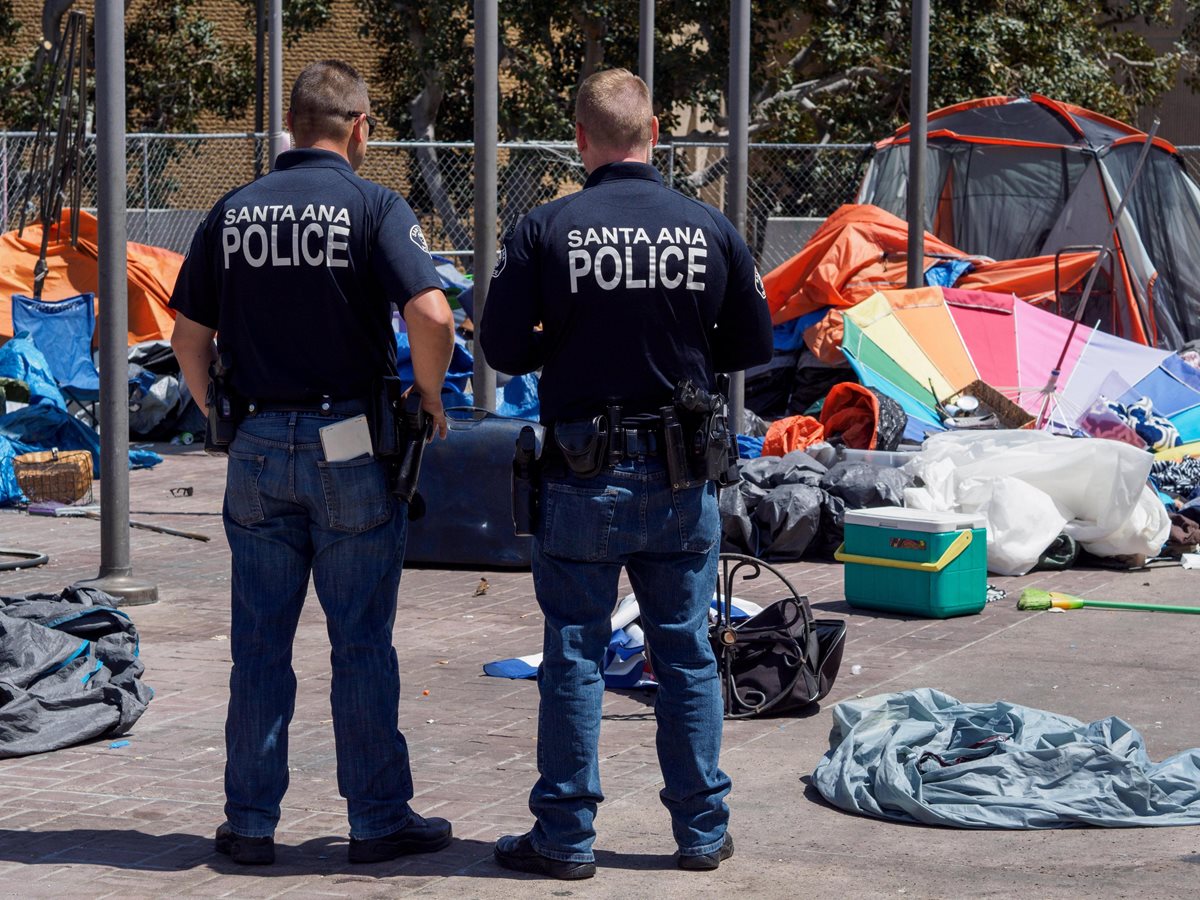 Efectivos de la policía miran los restos de un campamento de personas sin hogar del Condado de Orange. (EFE).