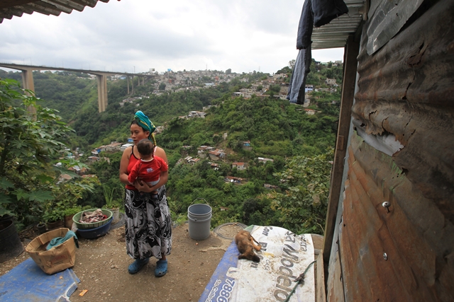 Romelia Gutiérrez carga a su hijo en el patio de su casa, en un barranco de la zona 7 capitalina. El peligro es evidente. (Foto Prensa Libre: Esbin García)