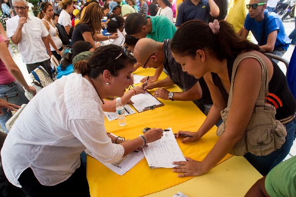 Venezolanos participan en la recolección de firmas. (EFE)