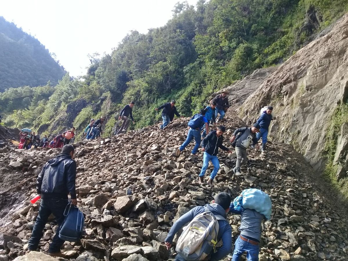 Un grupo de vecinos camina sobre las piedras que cayeron a la ruta en Vuelta al Aire, Chajúl, Quiché. (Foto Prensa Libre: Héctor Cordero)