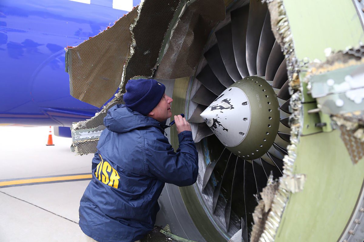 Un investigador de la NTSB en escena examinando los daños al motor del avión de Southwest Airlines.(AFP).