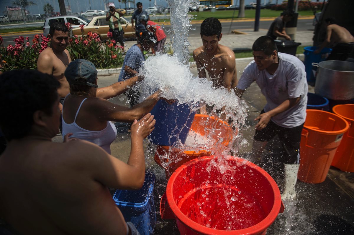 Peruanos aprovechan el agua distribuida por un camión recolector en Lima. (Foto Prensa Libre: AFP)