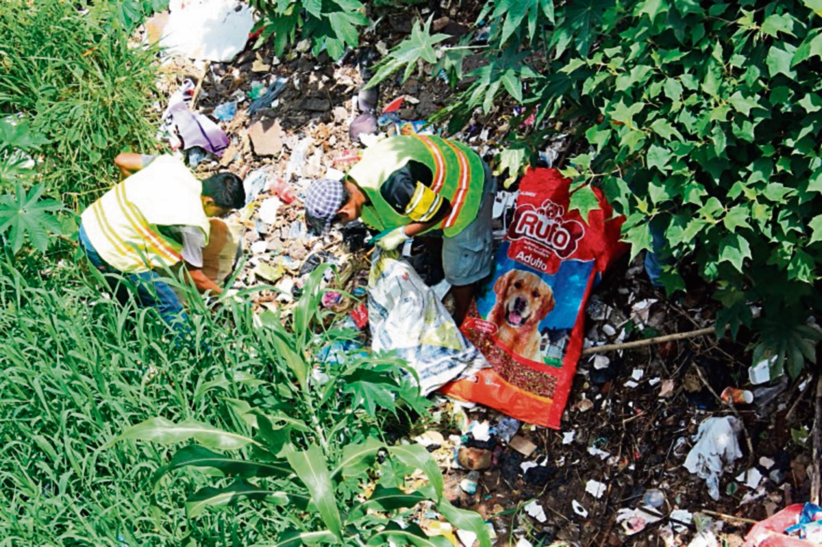 Los recolectores de desechos retiran  basura de abajo del puente sobre el río  La Virgen.