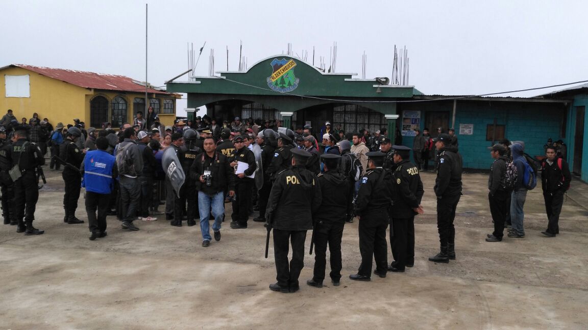 Agentes de la PNC y fiscales del MP dialogan con los comunitarios para intentar retomar el control. (Foto Prensa Libre: Ángel Julajuj).