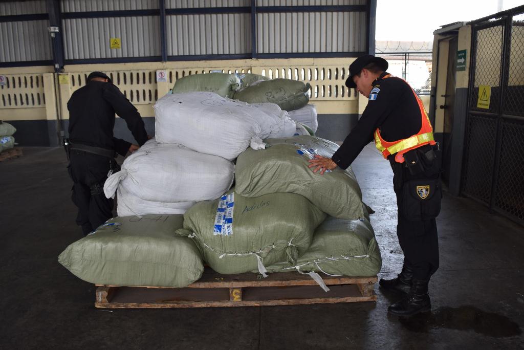 Dos agentes de la PNC inspeccionan parte de la mercadería decomisada en Escuintla. (Foto Prensa Libre: Enrique Paredes)