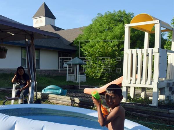 Hilda Ramírez, observa a su hijo Iván mientras juega en una piscina de plástico. (Foto Prensa Libre: EFE)