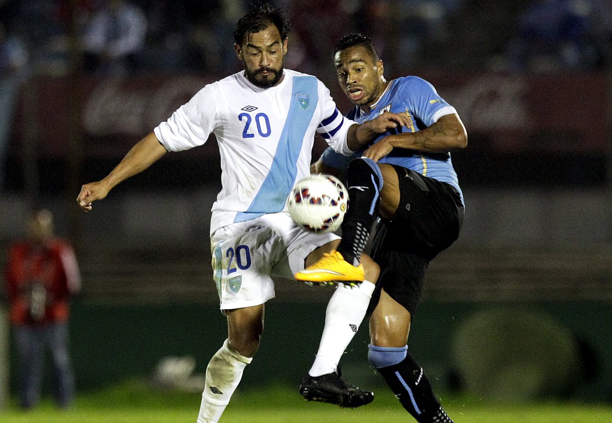 Carlos Ruiz disputa el balón con Álvaro Pereira durante el partido. (Foto Prensa Libre: AP)