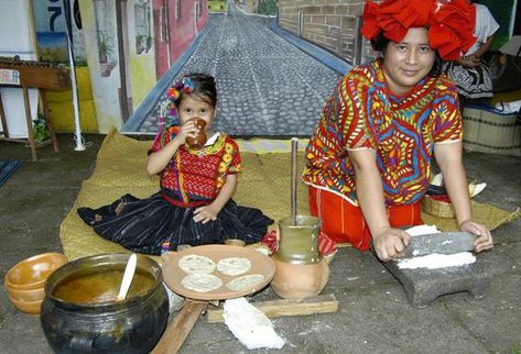 La estudiante Gladys Gómez, vistiendo un traje chuj,  muestra la forma de moler el maíz en la piedra de moler, para la  elaboración de tortillas. (Édgar Girón)