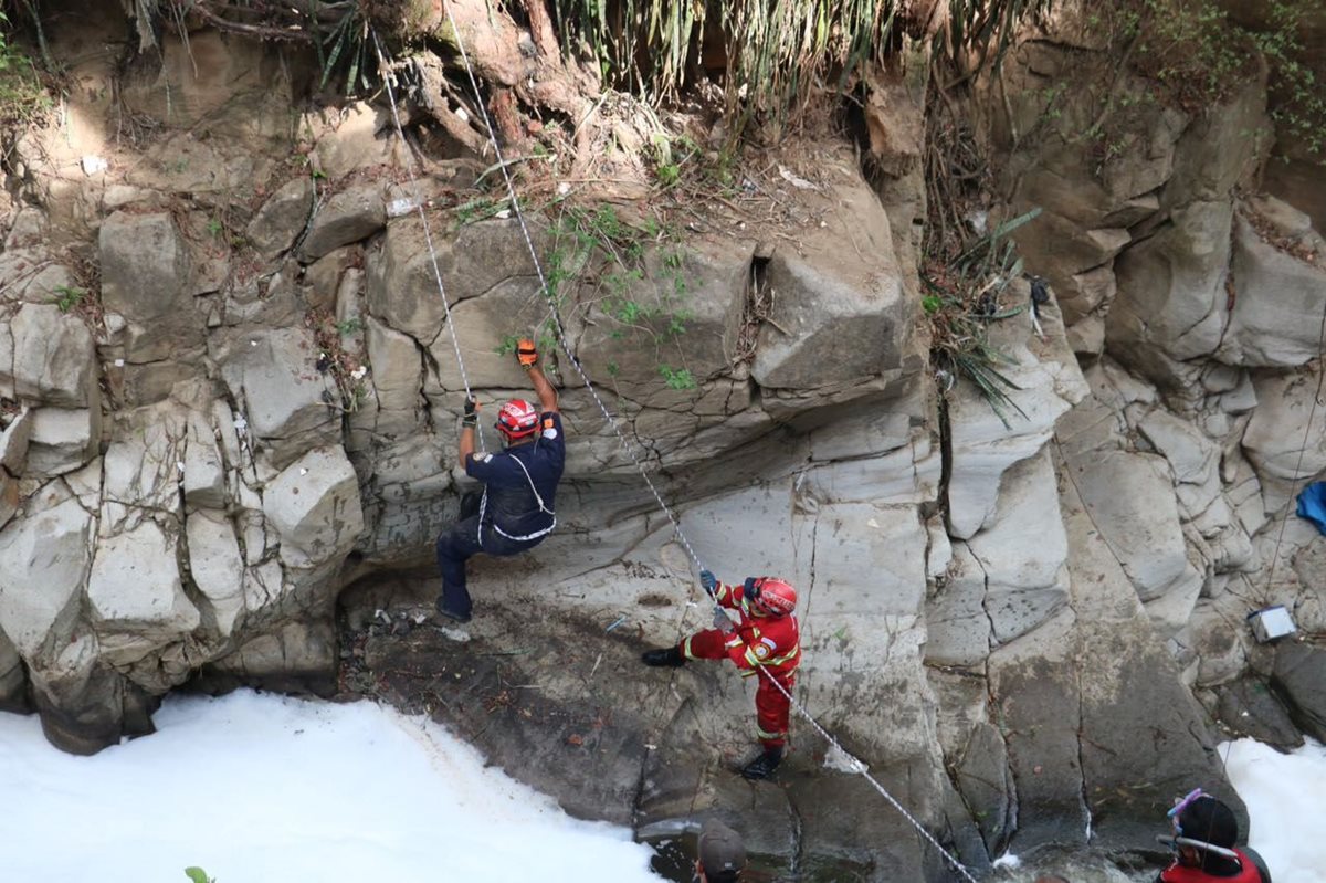 Dos bomberos sacan el cadáver del barranco donde cayó. (Foto Prensa Libre: CBM)