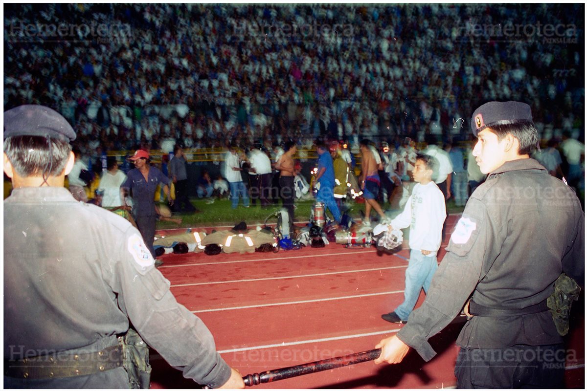 Bomberos Municipales y Voluntarios con la ayuda de particulares colocan en la pista de atletismo los cadáveres de las personas fallecidas en el Estadio Nacional Mateo Flores a causa de una avalancha humana en el Graderío General Sur. 16/10/1996 (Foto: Hemeroteca PL)