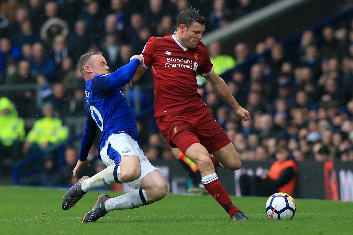 Wayne Rooney trata de detener a James Milner en el duelo entre el Liverpool y el Everton. Foto Prensa Libre: AFP)