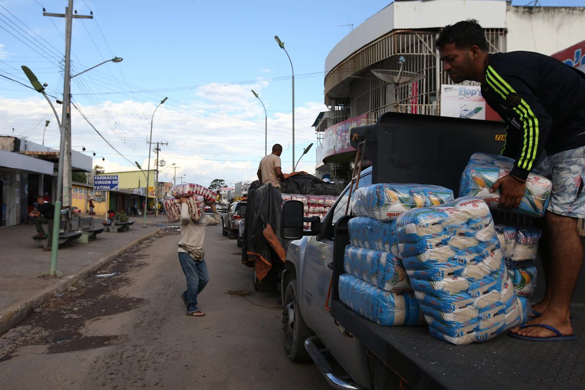 Un grupo de venezolanos se abastece de alimentos en la ciudad brasileña de Pacaraima fronteriza con Venezuela. (Foto Prensa Libre: EFE).