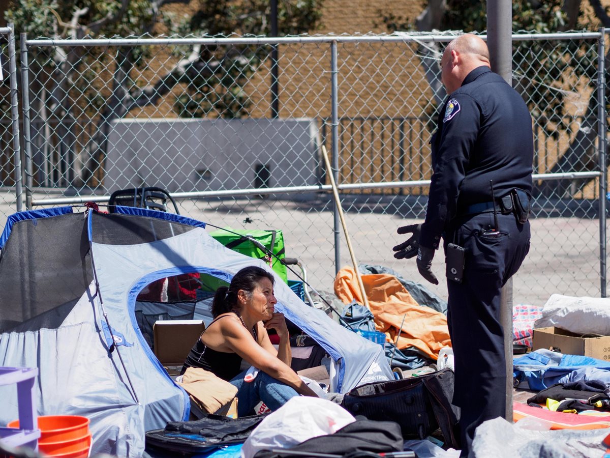 Un efectivo de la Policía le dice a Michele Salcedo (i) que deje su tienda en un campamento de personas sin hogar.(EFE).