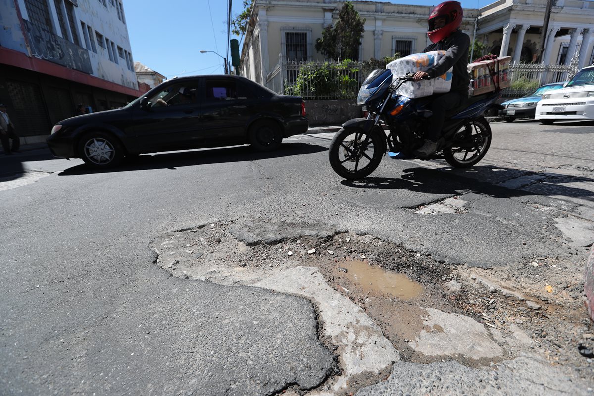 En pleno Centro Histórico, en la 3a. avenida y 13 calle, zona 1, se observan grandes agujeros en el asfalto. En la planificación de la comuna capitalina no se contempla el bacheo en ese sector. (Foto Prensa Libre: Érick Ávila)