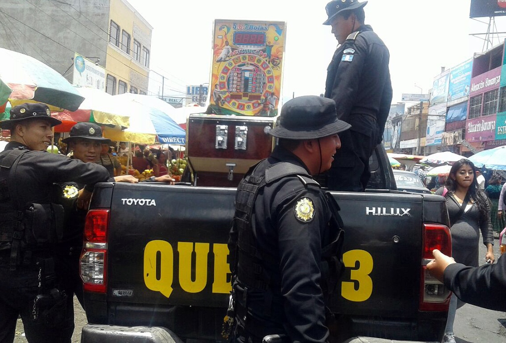 Agentes policiales cargan en palangana de autopatrulla máquinas traganíqueles, en Xela, Quetzaltenango. (Foto Prensa Libre: Carlos Ventura)