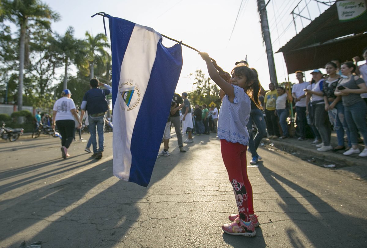 Una niña sostiene una bandera de Nicaragua durante la marcha masiva. (Foto Prensa Libre: EFE)