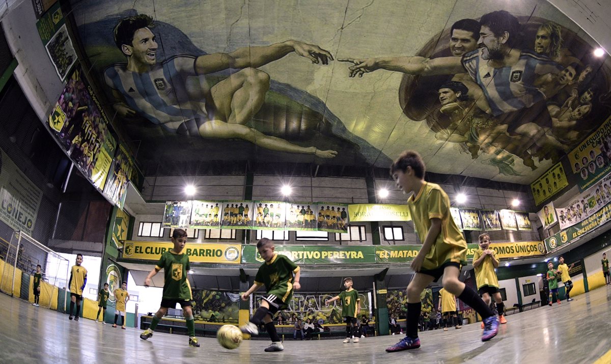 Los niños del Sportivo Pereyra de Barracas juegan bajo el mural de los astros argentinos. (Foto Prensa Libre: AFP)