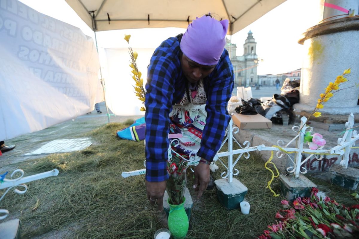 Carmen Urías, madre de una de las víctimas, acomoda las cruces blancas que recuerdan el nombre de las niñas. (Foto Prensa Libre: Érick Ávila)