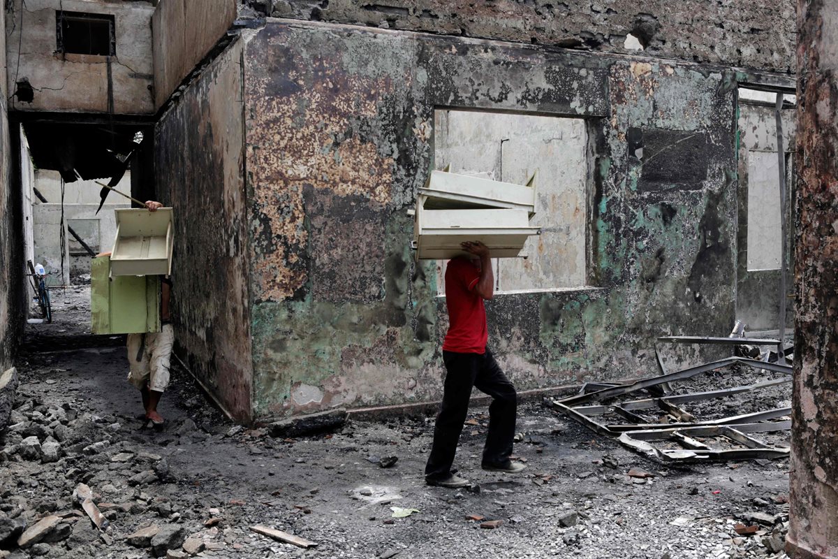 Pobladores rescatan algunos muebles de un local destruido tras protestas en Masaya, Nicaragua. (Prensa Libre: AFP)