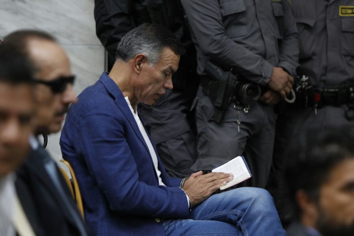 Juan de Dios Rodríguez lee la Biblia mientras espera la audiencia en la Sala de Vistas de la CSJ. (Foto Prensa Libre: Paulo Raquec)