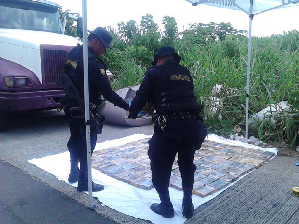 Agentes ordenan los paquetes localizados en un automotor, en Escuintla. (Foto Prensa Libre: PNC).