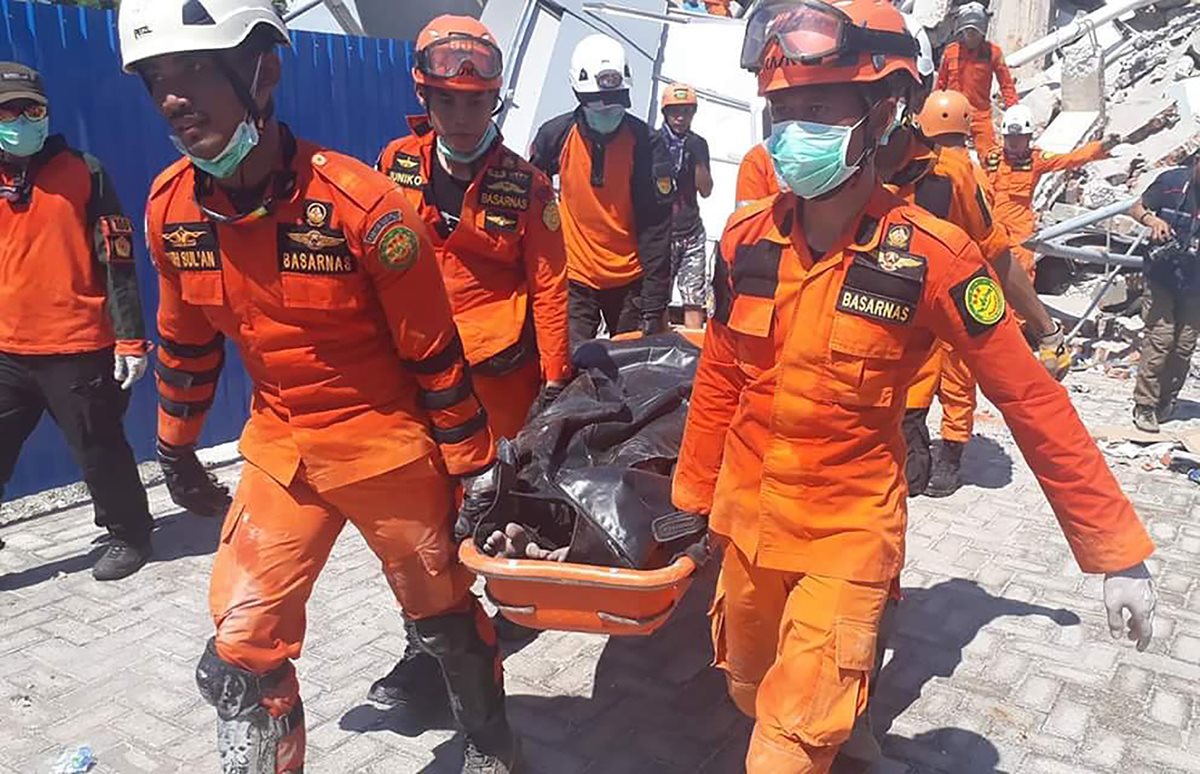 Rescatistas llevan un cuerpo que fue localizado entre los escombros de un edificio en Palu. (Foto Prensa Libre: AFP).