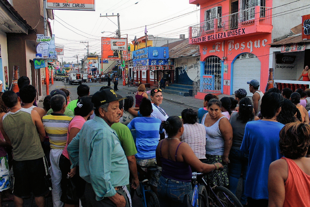 Curiosos observan el cadáver de Janet  Melgar, quien murió baleada en Puerto San José. (Foto Prensa Libre: Enrique Paredes)