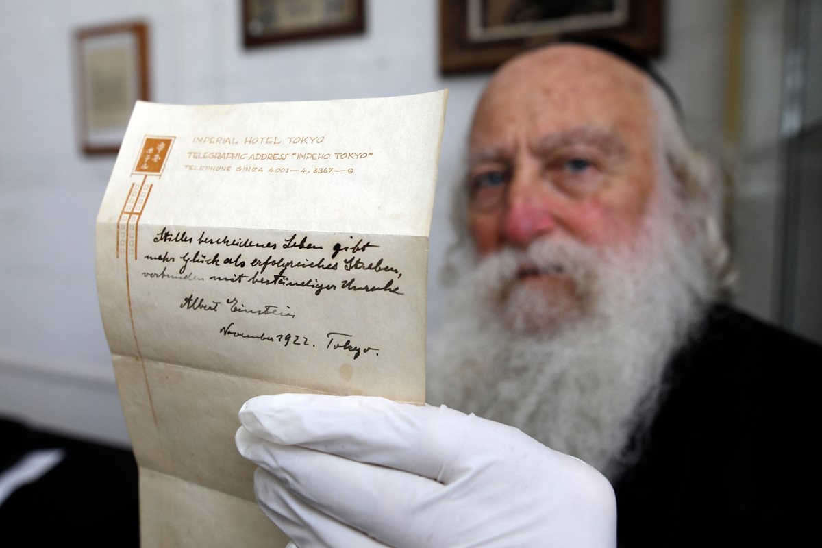 Un hombre sostiene la nota de Albert Einstein en la que escribe la Teoría de la Felicidad, que fue subastada por una cifra millonaria (Foto Prensa Libre: AFP).