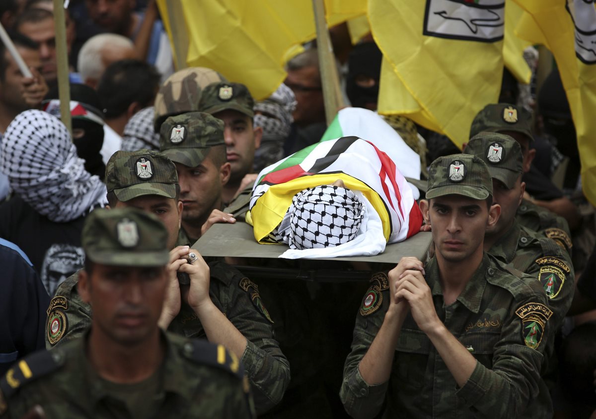 Solados palestinos cargan el cadáver de un niño de 13 años que murió el sábado último por disparos de Israel. (Foto Prensa Libre: EFE).