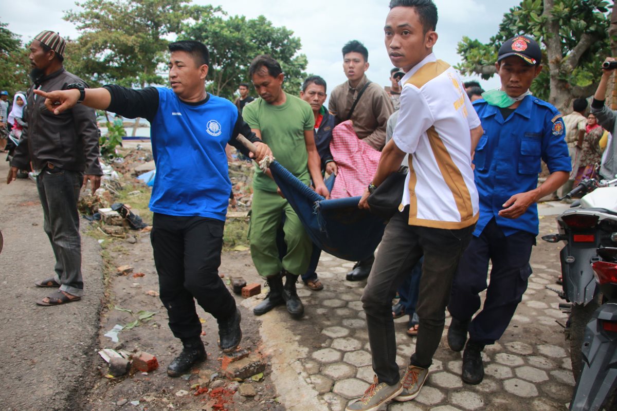 Voluntarios rescatan varios cadáveres de víctimas tras el impacto del tsunami en Indonesia.