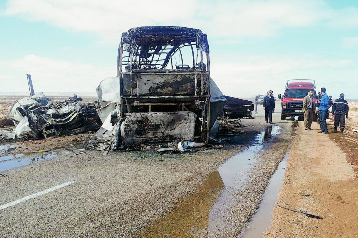 Investigadores observan el área donde ocurrió el siniestro. El bus quedó completamente incinerado. (Foto Prensa Libre: AFP).