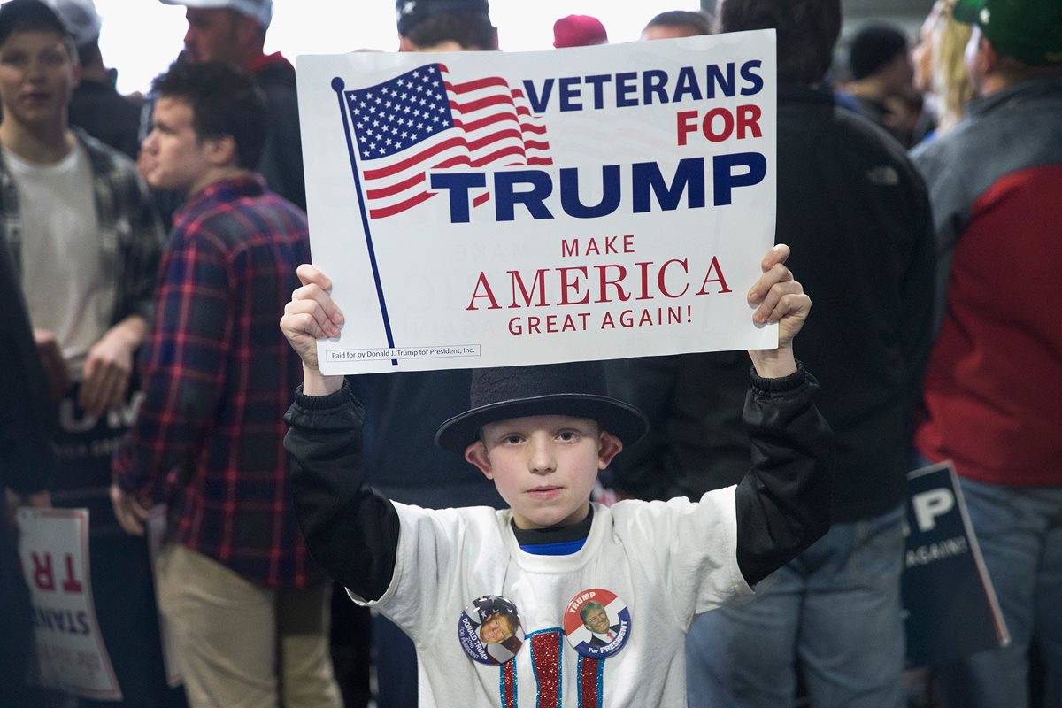 Un niño sostiene una pancarta de apoyo a Donald Trump. (Foto Prensa Libre: AFP).