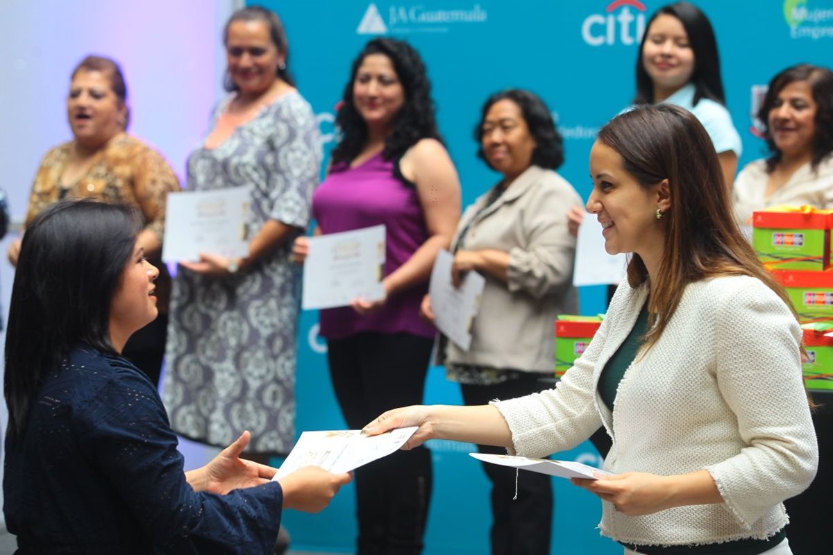 Isabel Martínez, gerente de mercadeo del Centro Comercial Portales, -de blanco- entrega diploma a una de las beneficiadas. (Foto Prensa Libre: Álvaro Interiano).