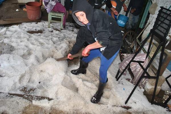 Vecino de San Andrés Xecul remueve el granizo en su hogar. (Foto: José Diego Puac /elQuetzalteco)