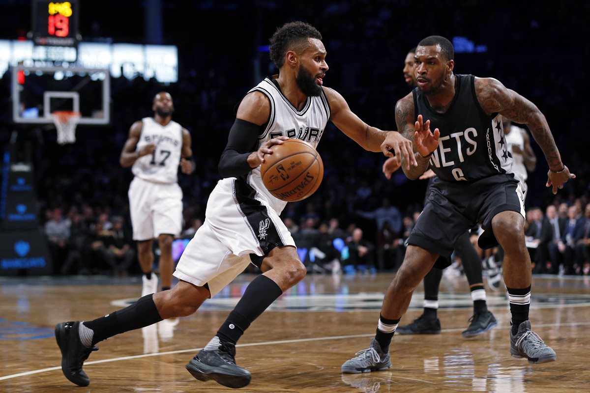 Patty Mills intenta dominar el balón ante la marca de Sean Kilpatrick. (Foto Prensa Libre: AFP)